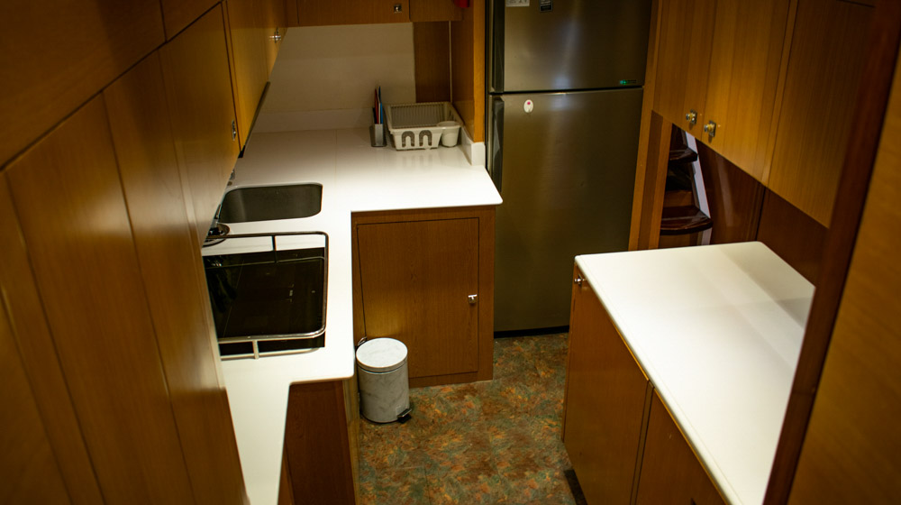 yacht galley with cooktop, refrigerator, cabinets and wooden furnishing